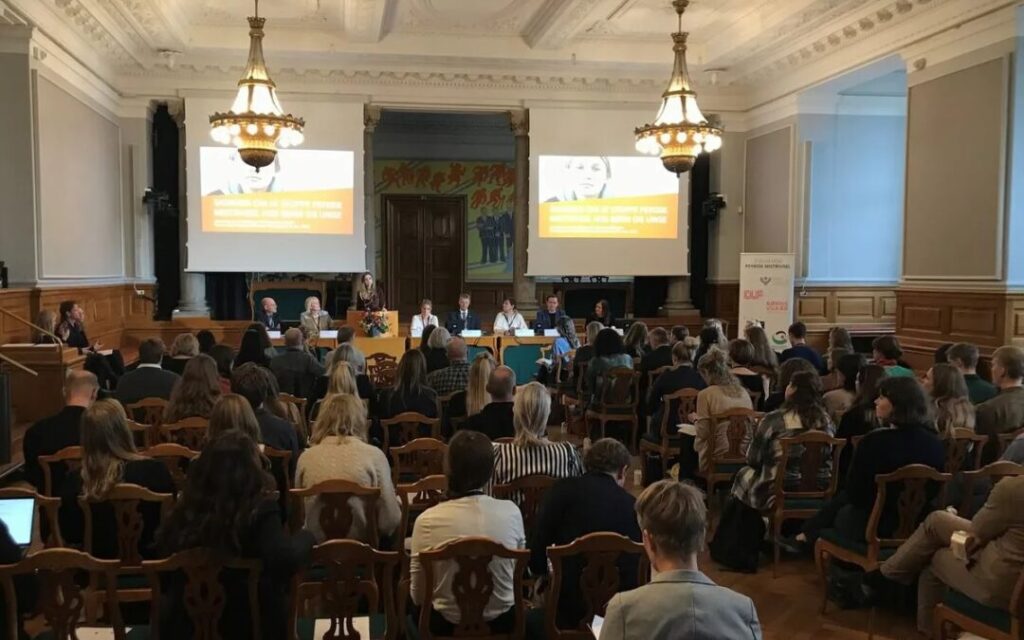 Politikere og eksperter sidder ved panelbord i stor sal og diskuterer indsatser om børn og unge med synshandicap.